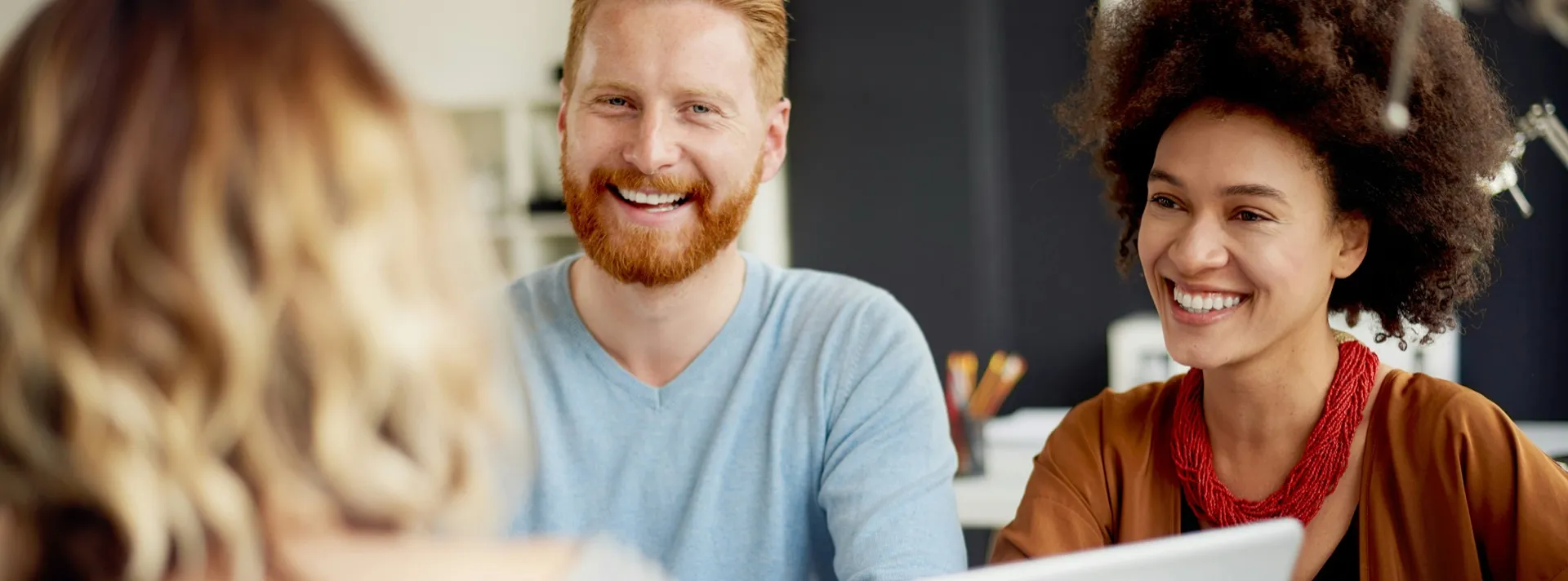 Smiling colleagues talking together around a laptop in a bright office